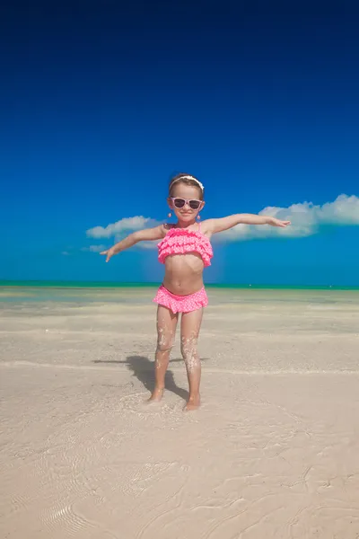 Klein meisje verspreiden haar armen permanent op het witte strand — Stockfoto