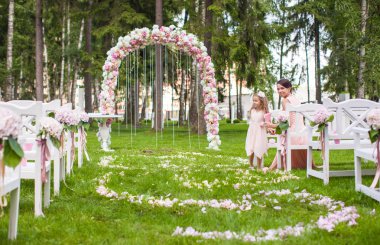 Wedding benches with guests and flower arch for ceremony outdoors clipart