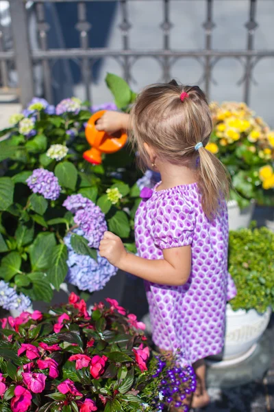 Kleines nettes Mädchen, das Blumen mit einer Gießkanne gießt — Stockfoto