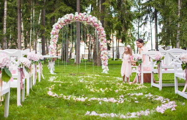 Svatba lavičky s hosty a květiny oblouk pro venkovní obřad — Stock fotografie