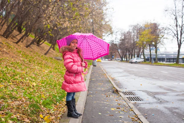 Kleines Mädchen läuft unter einem Regenschirm im herbstlichen Regentag — Stockfoto