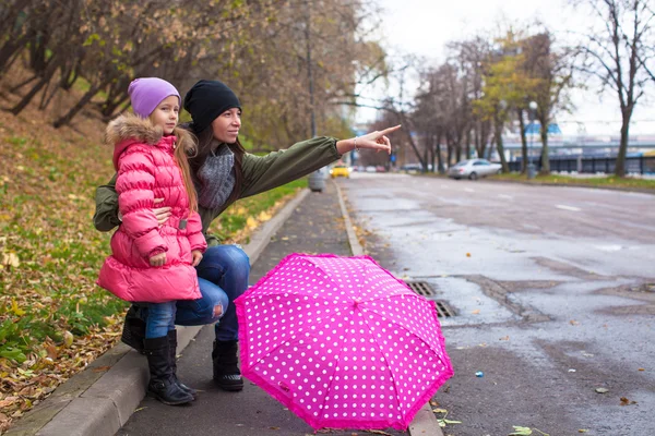 Klein meisje en haar?? moeder lopen met paraplu op een regenachtige dag — Stockfoto