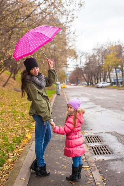 Ragazzina che cammina con la madre accompagnatrice sotto un ombrello in una giornata piovosa — Foto Stock