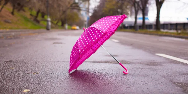 Parapluie rose pour enfants sur l'asphalte humide à l'extérieur — Photo