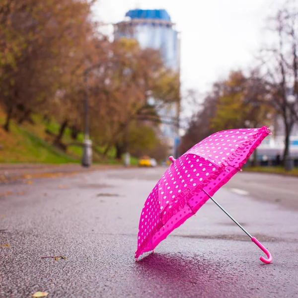 Çocuk şemsiye açık havada ıslak asfalt üzerinde pembe — Stok fotoğraf