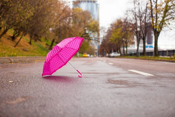 Parapluie rose pour enfants sur l'asphalte humide à l'extérieur — Photo