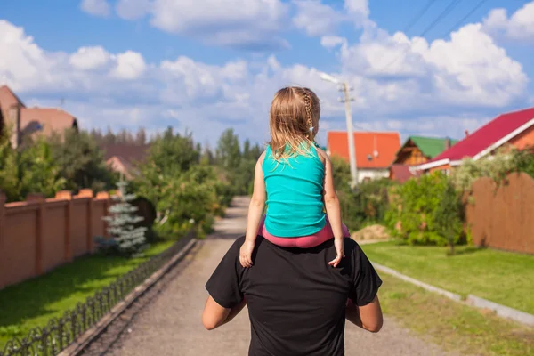 Liten flicka rider på ung pappa utomhus — Stockfoto