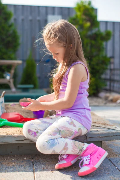 Little cute girl playing at the sandbox with toys in yard — Stock Photo, Image