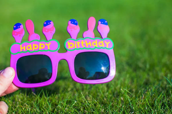 Rode gelukkige verjaardag bril op het gras — Stockfoto