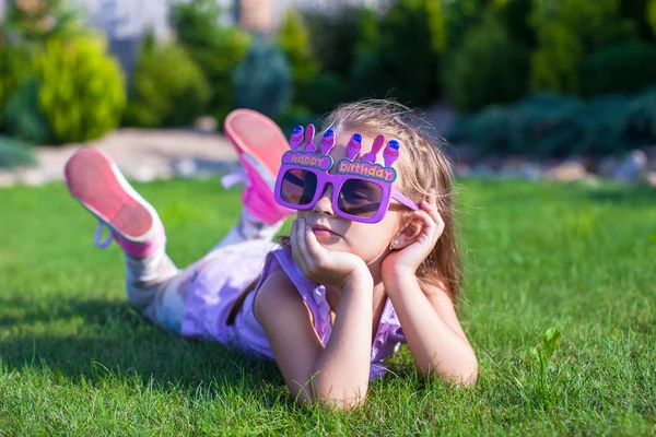 Entzückendes kleines Mädchen mit Happy Birthday Brille, die draußen lächelt — Stockfoto