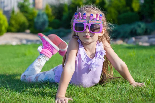 Adorable niña en gafas de feliz cumpleaños sonriendo al aire libre —  Fotos de Stock