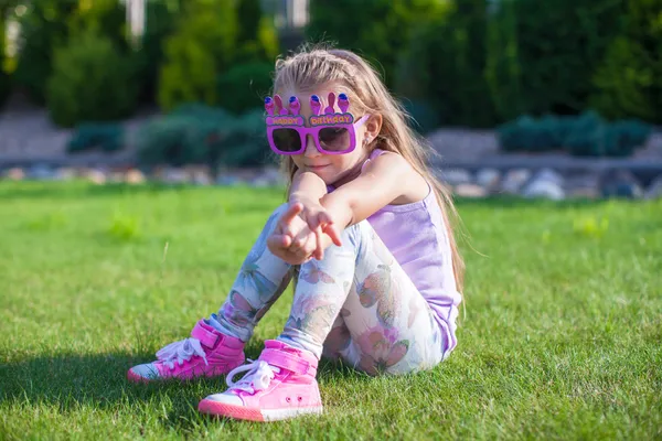 Adorable niña con gafas de feliz cumpleaños sonriendo al aire libre —  Fotos de Stock