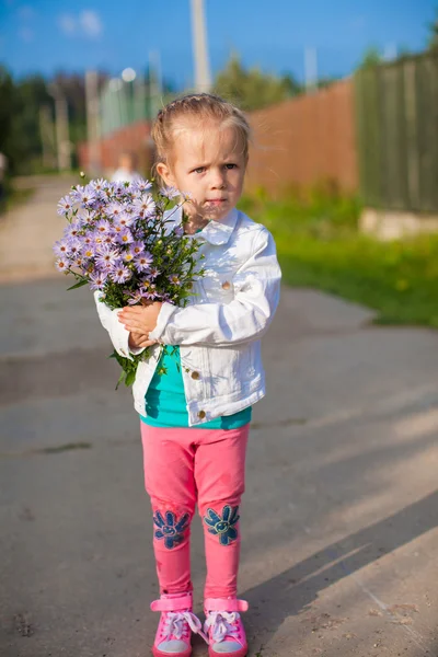 Niña linda caminando con un ramo de flores —  Fotos de Stock