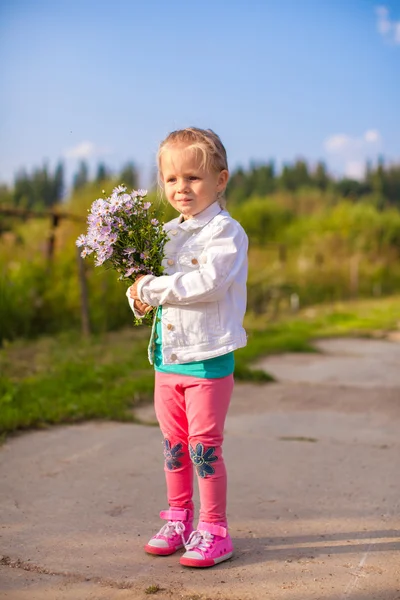 Niña linda caminando con un ramo de flores —  Fotos de Stock