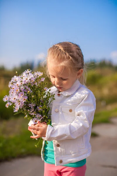Petite fille mignonne marchant avec un bouquet de fleurs — Photo