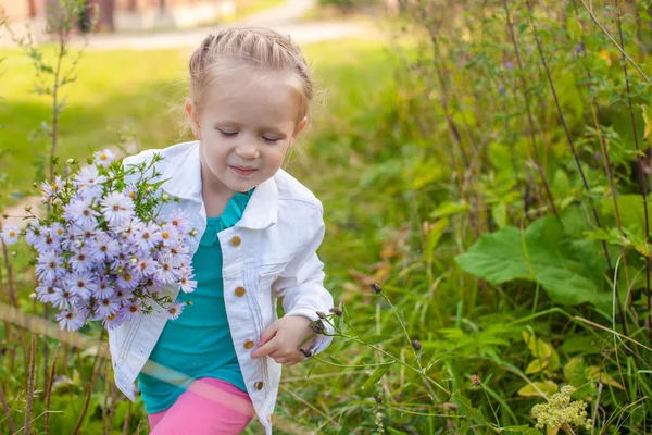 Liten söt flicka gå med en bukett blommor — Stockfoto
