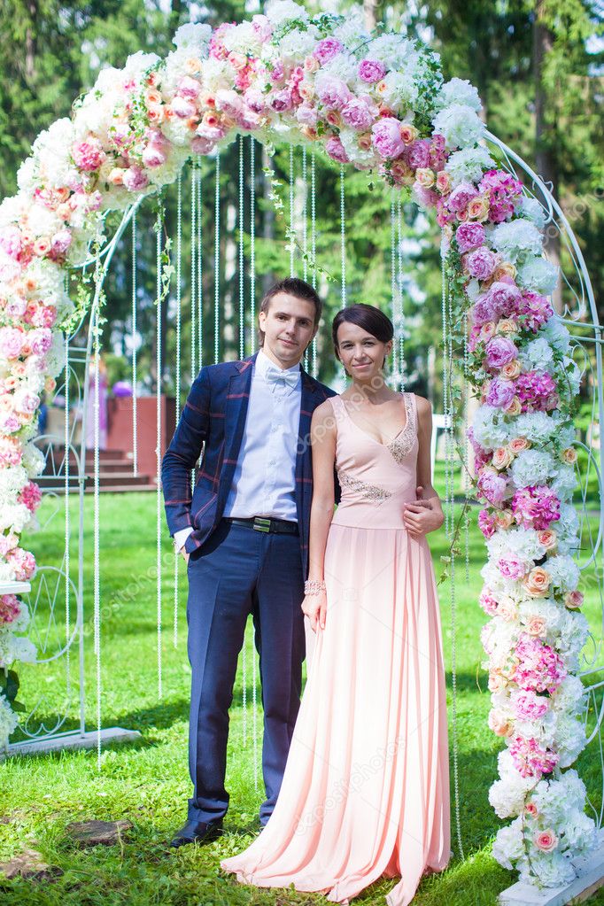 Lovely young couple in a flower arch at the wedding ceremony