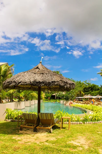 Reposero bajo un paraguas en el hotel cerca de la piscina en Seychelles —  Fotos de Stock