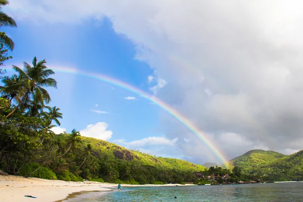 Sateenkaari trooppisen saaren yllä ja valkoinen ranta Seychelleillä — kuvapankkivalokuva