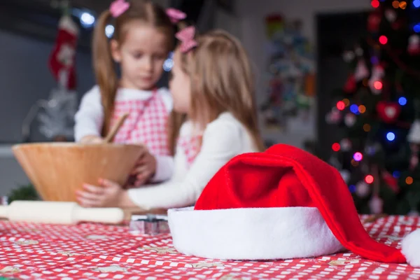 Santa hatt bakgrund av två lilla flicka baka julkakor — Stockfoto