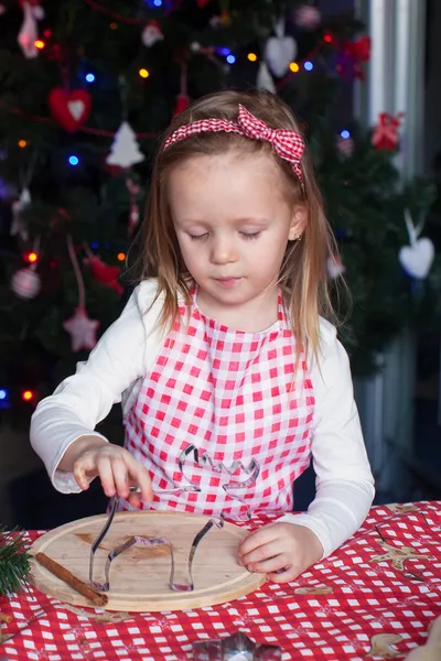 Adorabile bambina che cuoce biscotti di pan di zenzero per Natale in cucina — Foto Stock