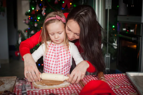 Маленькая девочка с молодой матерью пекут рождественские пряники вместе — стоковое фото