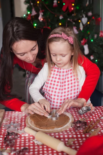 一緒にクリスマスのジンジャーブレッドのクッキーを焼く美しい母親と小さな女の子 — ストック写真