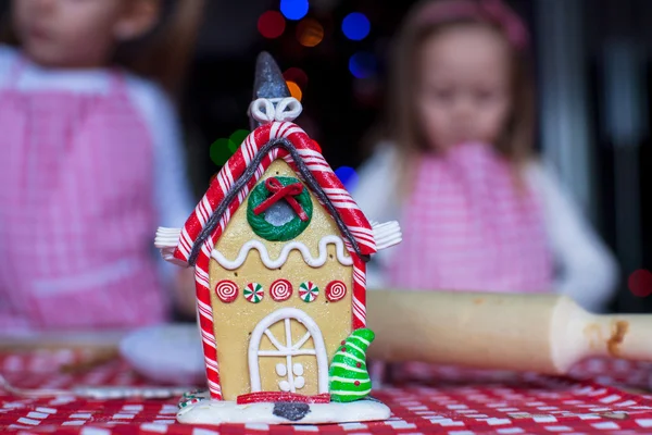 Gingerbread fairy house decorated by colorful candies on a background of little girls