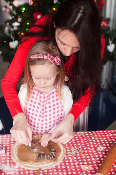 Menina com a jovem mãe assar biscoitos de gengibre de Natal juntos — Fotografia de Stock