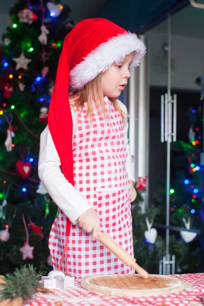 Adorable little girl with rolling pin baking gingerbread cookies for Christmas — Stock Photo, Image