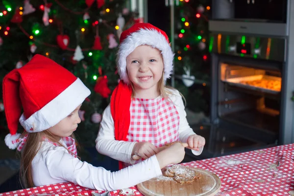 Små flickor baka pepparkakor i santa hatt — Stockfoto