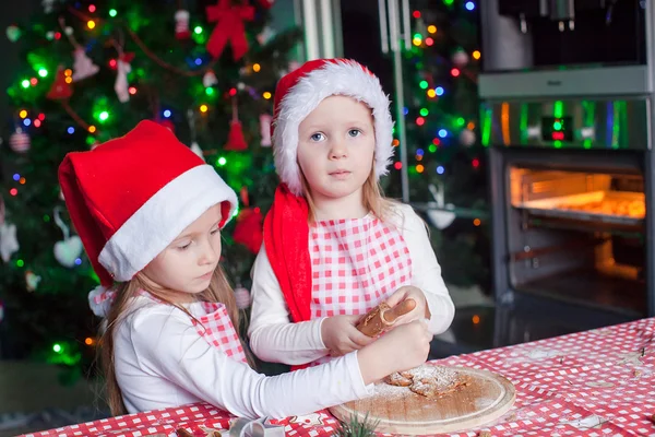 小さな女の子のクリスマスのサンタ帽子でジンジャーブレッド クッキーを焼く — ストック写真