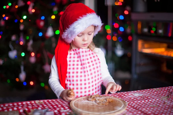 Adorable little girl eating the dough for ginger cookies in kitchen — Stock Photo, Image