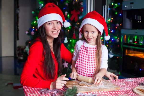 Щаслива сім'я в Санта-капелюхах випікає різдвяні пряники разом — стокове фото