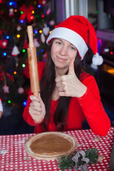 Mujer joven en sombrero de Navidad hornear pan de jengibre en casa —  Fotos de Stock