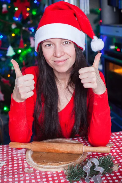 Young woman in Christmas hat raised thumbs up at home — Stock Photo, Image