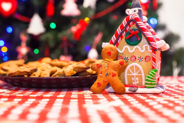 Söta pepparkakor mannen framför hans godis ingefära hus bakgrund julgransljus — Stockfoto