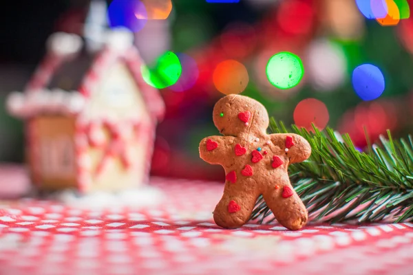 Primo piano di pan di zenzero uomo sfondo caramelle casa zenzero e albero di Natale luci — Foto Stock