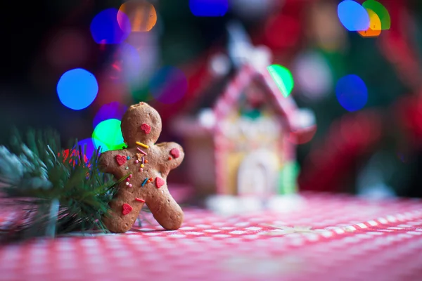 Närbild av gingerbread man bakgrunden godis ingefära hus och julgran lampor — Stockfoto