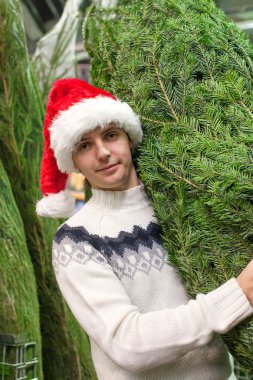 Noel ağacı satın santa şapka genç adam portresi