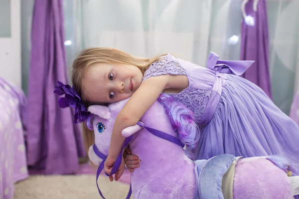 Adorable niña con un caballo de juguete en casa — Foto de Stock