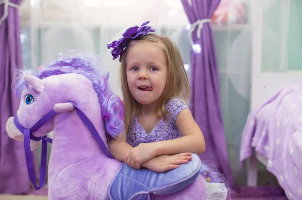 Linda niña divertida jugando con un caballo de juguete en casa — Foto de Stock