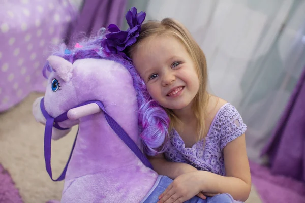 Linda niña feliz jugando con un caballo de juguete en casa — Foto de Stock