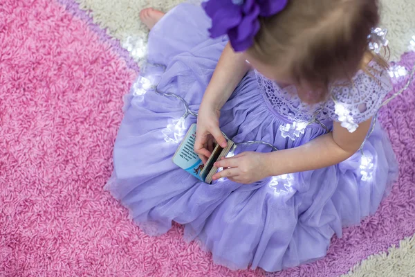 Liten bedårande flicka i vacker klänning bland kransar hemma — Stockfoto