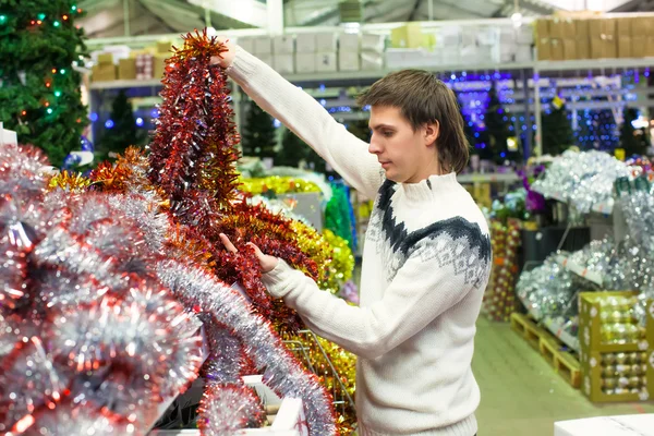 Young man choosing decorations on the Christmas tree — Stock Photo, Image