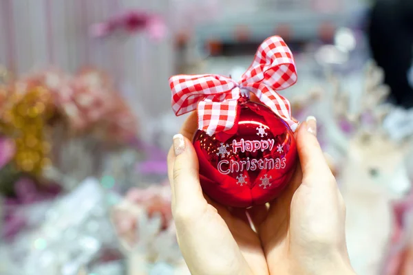 Hermosa bola roja en las manos de una mujer joven para Navidad — Foto de Stock