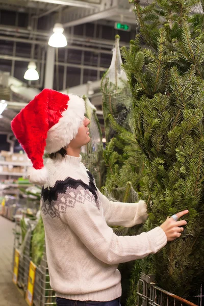 Junger Vater mit Weihnachtsmütze kauft Weihnachtsbaum — Stockfoto