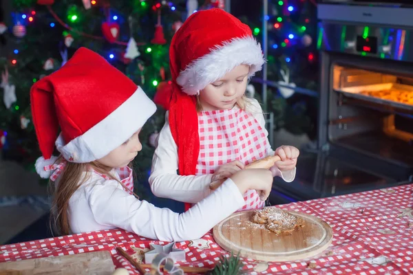 Kleine Mädchen in Weihnachtsmützen backen weihnachtliche Lebkuchen — Stockfoto
