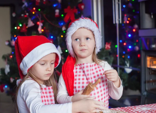 二人の少女が家庭でクリスマスのジンジャーブレッドのクッキーを作る — ストック写真