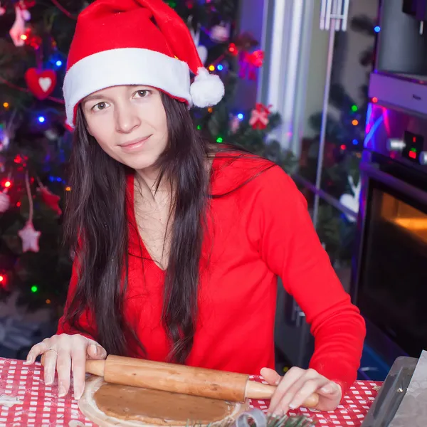 Mujer joven en sombrero de Navidad hornear pan de jengibre en casa —  Fotos de Stock